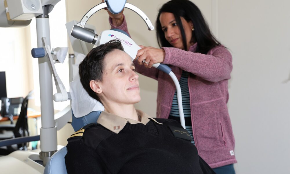 U.S. Navy Lt. (Dr.) Meghan Quinn (seated), a psychiatrist and chief of the Partial Hospitalization Program (PHP) at Walter Reed and Dr. Vanessa Torres-Llenza, staff psychiatrist at PHP, demonstrate the use of Transcranial Magnetic Stimulation (TMS), which can help treat depression and anxiety. (DOD photo by Quinton Lyons)