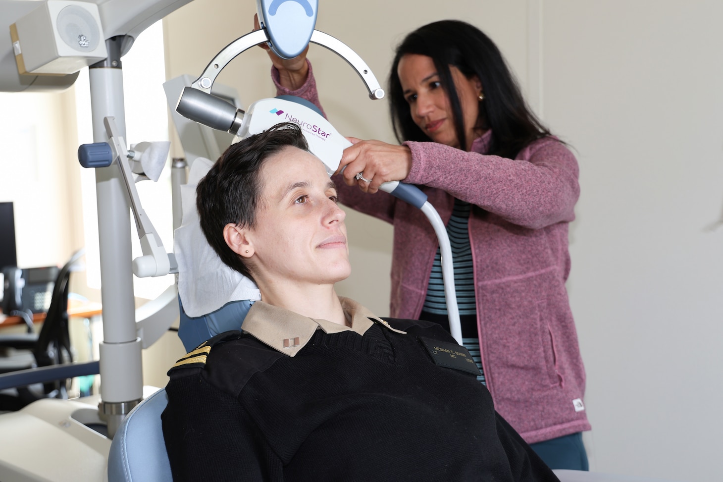 U.S. Navy Lt. (Dr.) Meghan Quinn (seated), a psychiatrist and chief of the Partial Hospitalization Program (PHP) at Walter Reed and Dr. Vanessa Torres-Llenza, staff psychiatrist at PHP, demonstrate the use of Transcranial Magnetic Stimulation (TMS), which can help treat depression and anxiety. (DOD photo by Quinton Lyons)