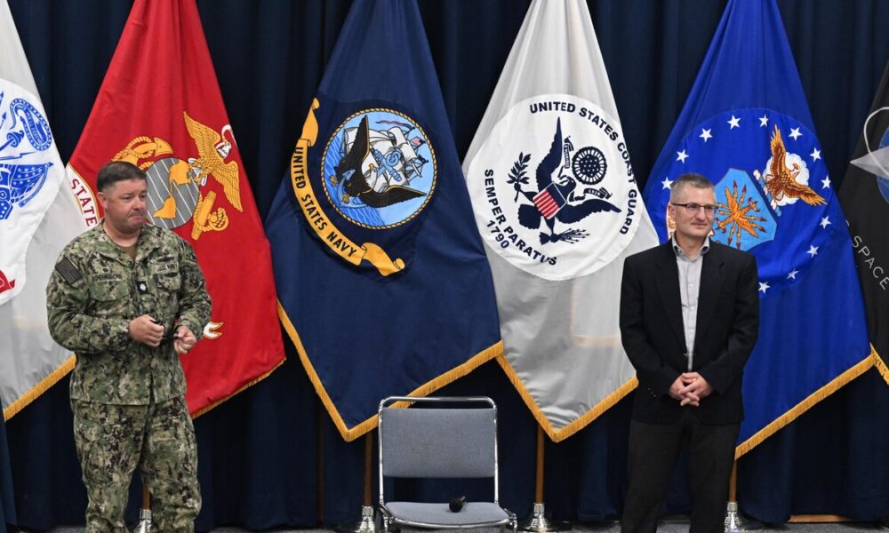 DAHLGREN, Va. (July 08, 2024) Cmdr. Jonathan Schermerhorn, commanding officer, Surface Combat Systems Training Command AEGIS Training and Readiness Center (SCSTC ATRC), discusses Mr. Jeff Noordyk’s, SCSTC ATRC’s director of Training, contributions to the schoolhouse and the Aegis community during a farewell event onboard Naval Support Facility Dahlgren, Virginia.  (U.S. Navy photo by Michael Bova)