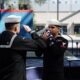 Sailors salute the ensign during a retirement ceremony in  Pensacola, Fla.